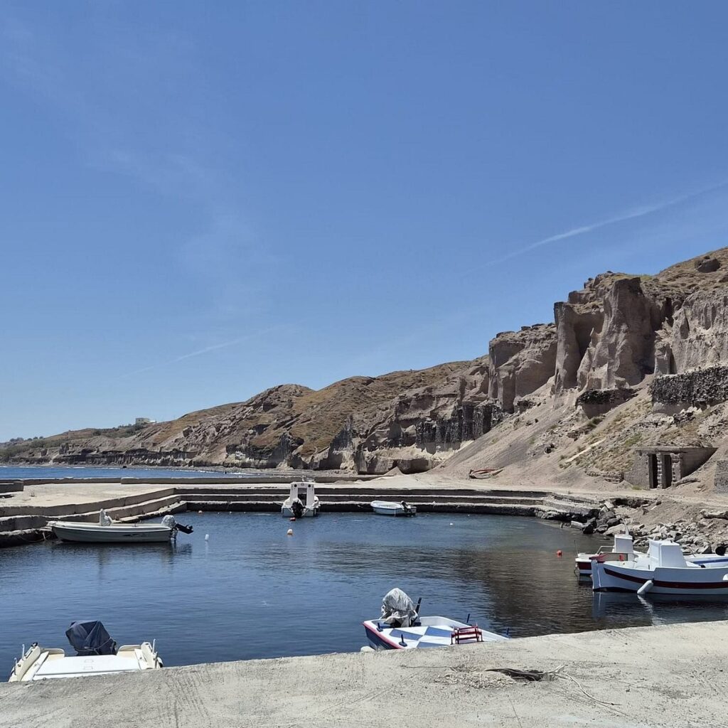 Vourvoulos port black pebble beach and traditional seafood tavern Santorini⁠
